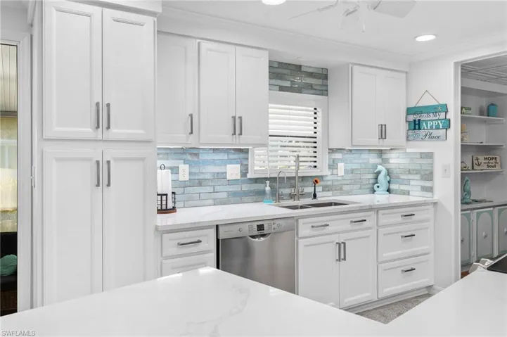 Kitchen featuring backsplash, ornamental molding, sink, dishwasher, and white cabinetry