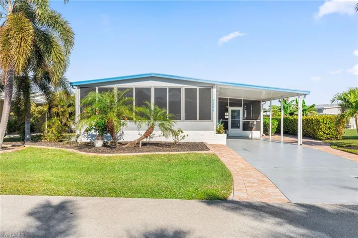 View of front of property with a carport, a sunroom, and a front lawn