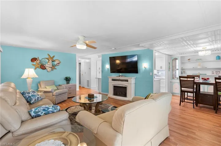 Living room with ceiling fan, light wood-type flooring, built in shelves, and a premium fireplace
