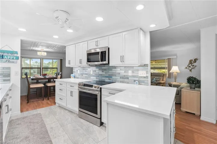 Kitchen featuring tasteful backsplash, light hardwood / wood-style flooring, white cabinets, and stainless steel appliances