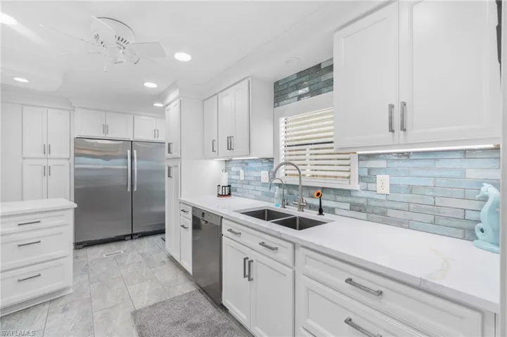 Kitchen featuring ceiling fan, sink, tasteful backsplash, white cabinets, and appliances with stainless steel finishes