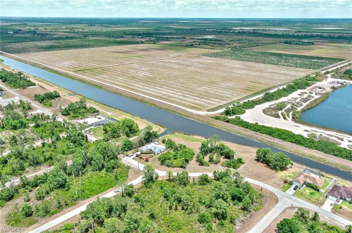 Aerial view of sparsely populated area with a nearby body of water and extensive farmland