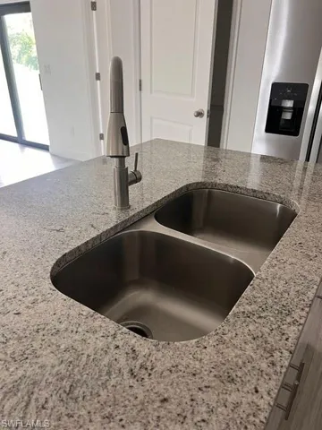 Kitchen view of light stone countertops and stainless steel refrigerator with ice dispenser
