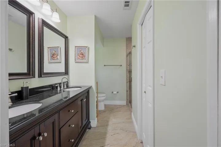 Owner's bath with double sink vanity, walk in closet, and updated shower