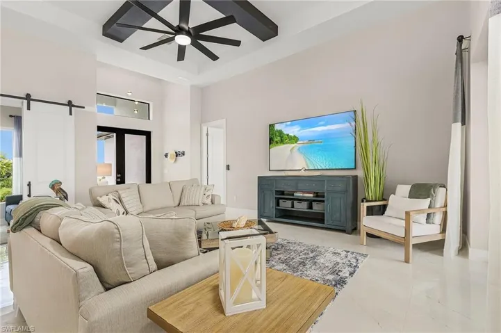 Living room featuring a ceiling fan, a barn door, a raised ceiling.
