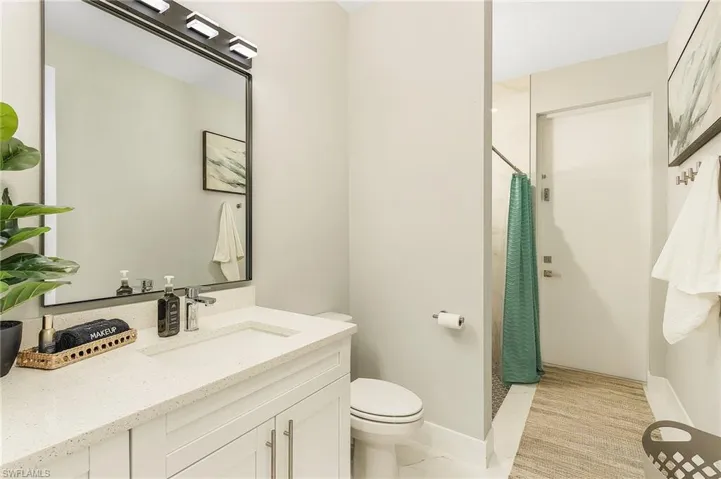 Full bath with vanity, baseboards, curtained shower, and toilet.