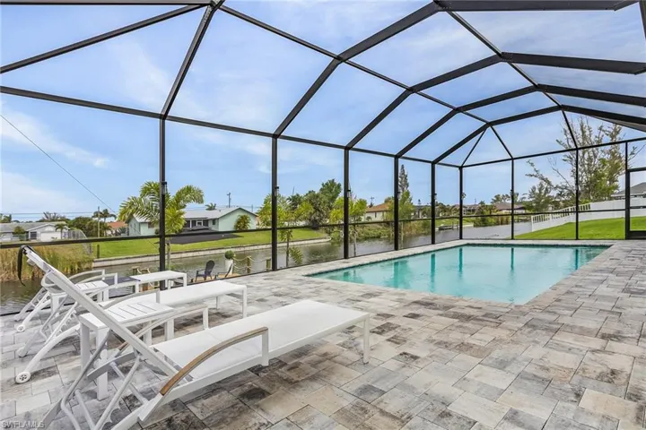 Outdoor pool featuring screen enclosure, a water view, and a patio area