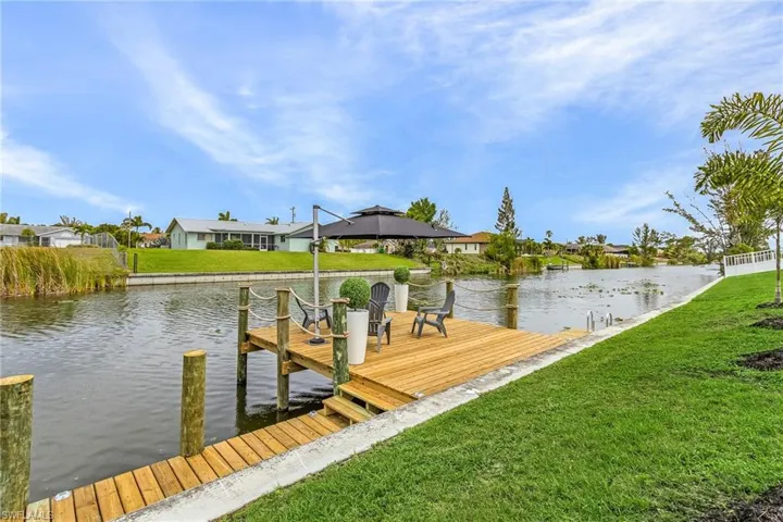 View of dock with a lawn, a water view.