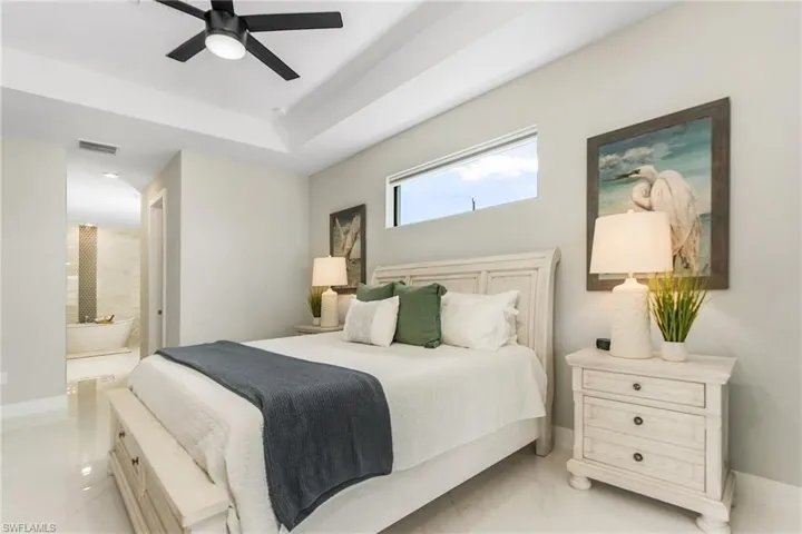 Primary Bedroom with a ceiling fan, marble finish floor, ensuite bath.