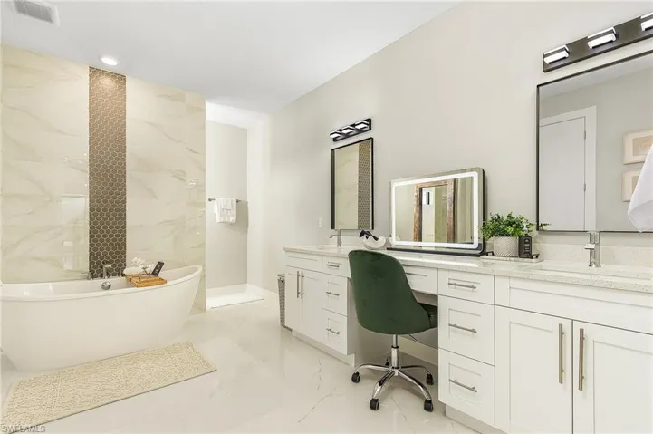Full bath featuring visible vents, a freestanding bath, marble finish floor, and vanity.