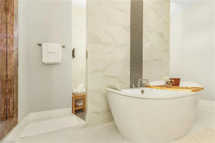 Primary Bathroom with a freestanding tub, walk in shower, and marble finish floor
