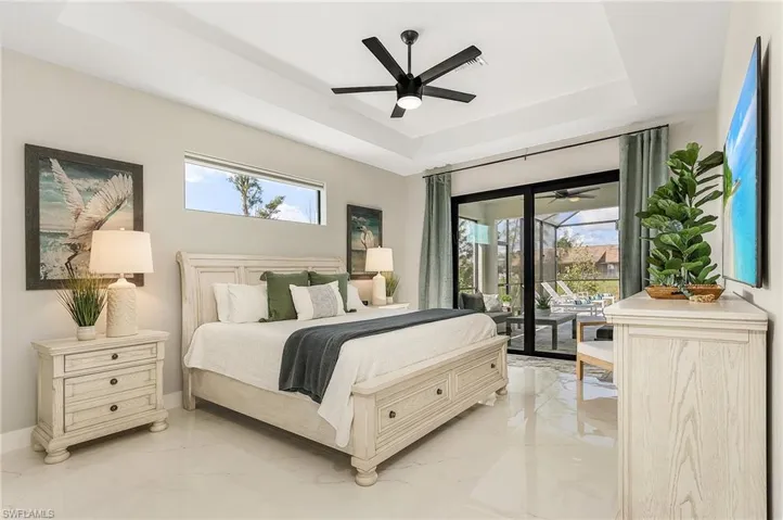 Primary Bedroom featuring a raised ceiling, access to outside, multiple windows, and marble finish floor