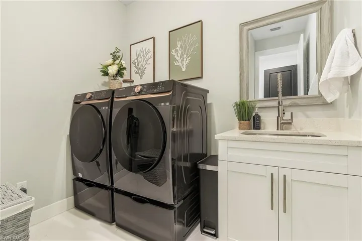 Washroom featuring a sink, visible vents, cabinet space, and washer and clothes dryer.