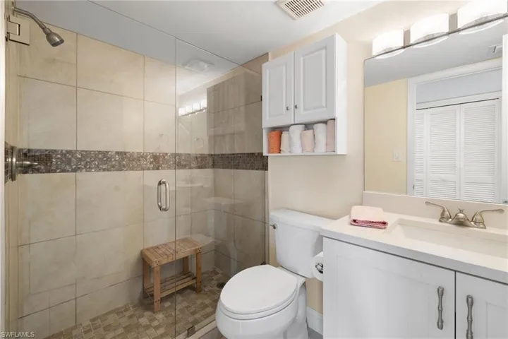 Full bath featuring vanity, a shower stall, and a closet