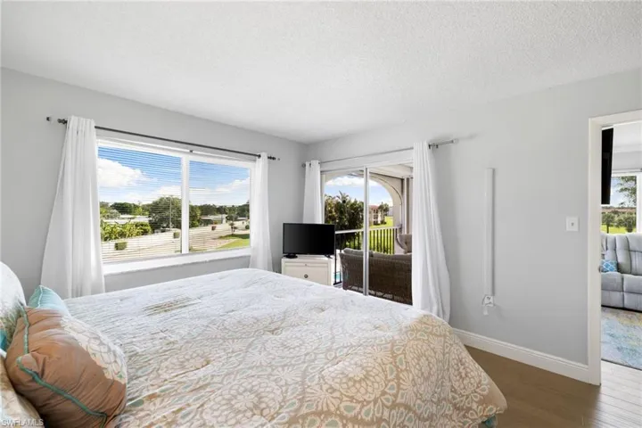 Bedroom with access to exterior, dark wood-style floors, and a textured ceiling