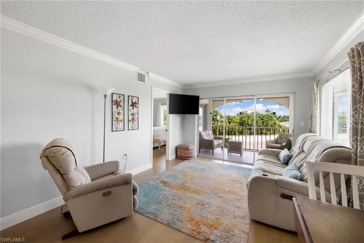 Living room featuring wood finished floors, ornamental molding, and a textured ceiling