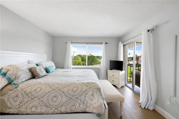 Bedroom with a textured ceiling, access to exterior, and wood finished floors