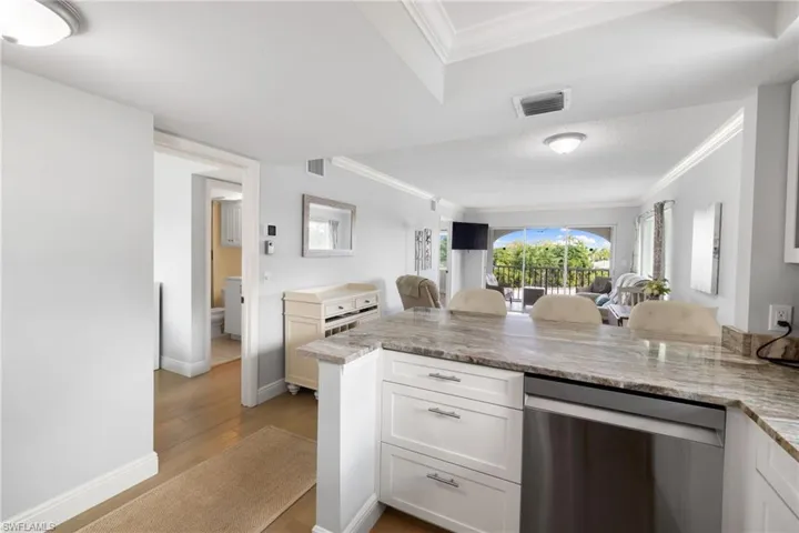 Kitchen featuring dishwasher, a kitchen breakfast bar, white cabinets, crown molding, and light wood-style floors