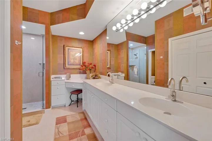 Bathroom with oversized vanity, dual sinks, toilet, tile flooring, and walk in shower