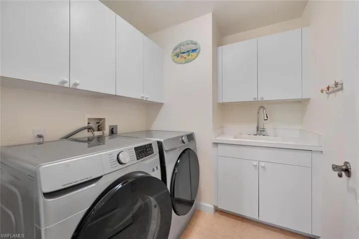 Laundry area featuring cabinets, washing machine and clothes dryer, hookup for an electric dryer, hookup for a washing machine, and sink