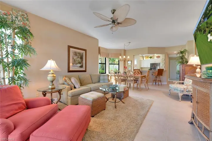 Tiled living room featuring ceiling fan with notable chandelier