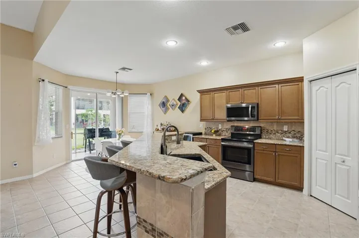 Kitchen with brown cabinetry, an inviting chandelier, visible vents, a sink, and appliances with stainless steel finishes