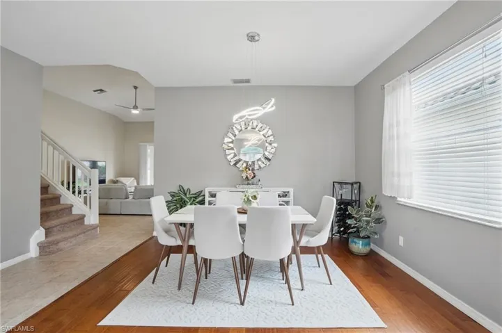 Dining space with baseboards, ceiling fan, visible vents, wood finished floors, and stairway