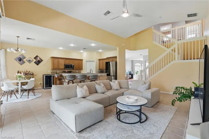 Living area with beverage cooler, light tile patterned floors, visible vents, and stairway