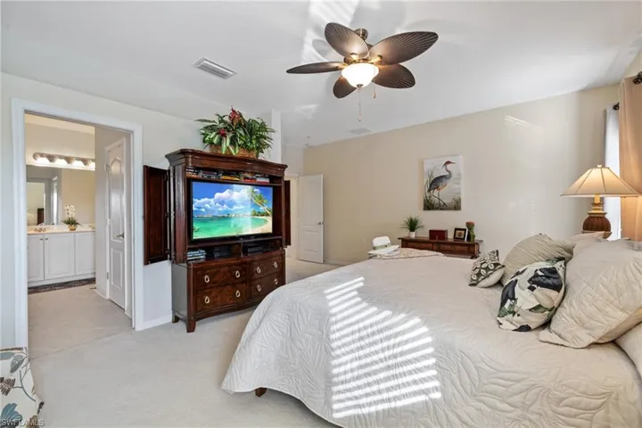 Main Bedroom with ensuite bathroom, light carpet, and ceiling fan