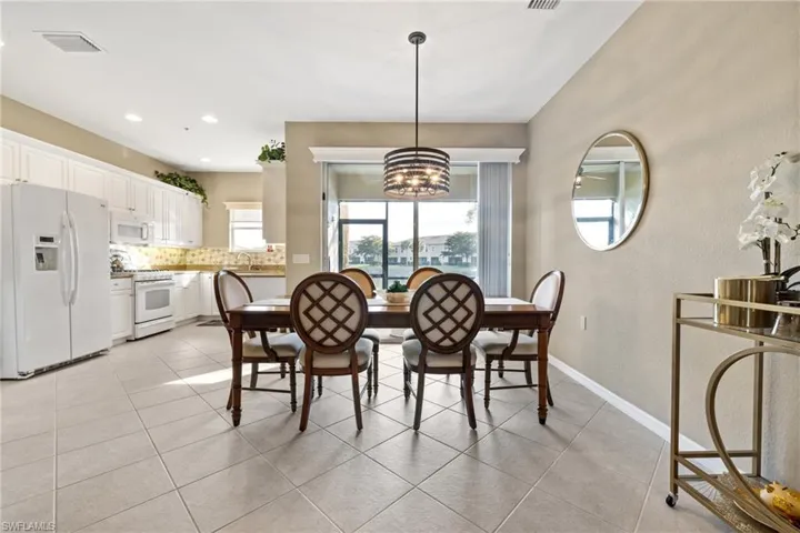 Dining space with vaulted ceiling, sink, light tile patterned floors, and a notable chandelier