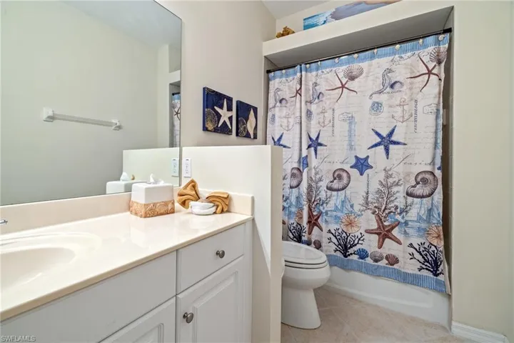 Full bathroom featuring tile patterned flooring, vanity, shower / bath combo with shower curtain, and toilet
