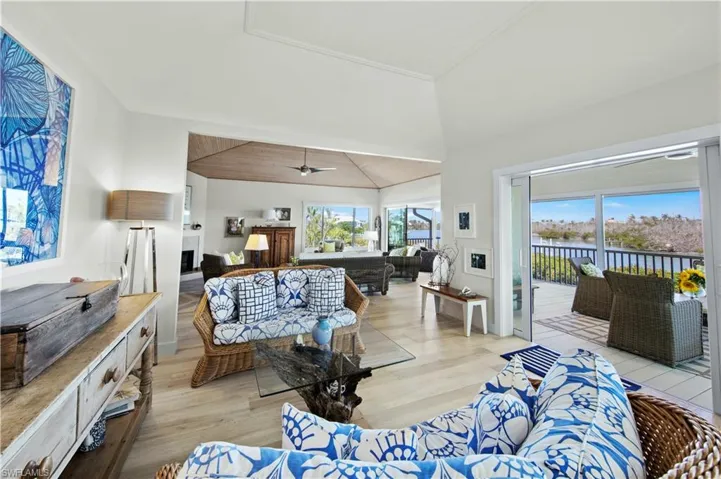 Living room featuring ceiling fan, a water view, high vaulted ceiling, and light hardwood / wood-style floors