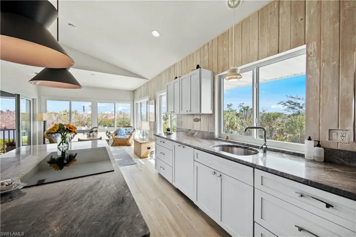 Kitchen with pendant lighting, dark stone countertops, sink, and white cabinets