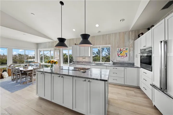 Kitchen with stainless steel oven, hanging light fixtures, black electric cooktop, a kitchen island, and white cabinets