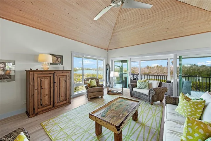 Living room with a wealth of natural light, wooden ceiling, high vaulted ceiling, and light hardwood / wood-style floors