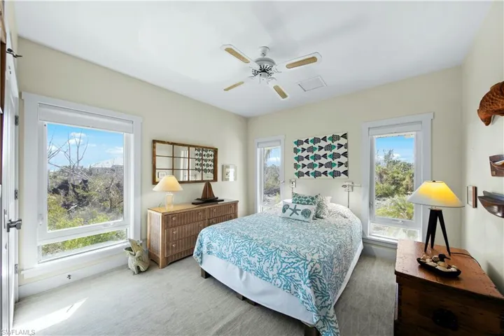 Carpeted bedroom featuring ceiling fan and multiple windows