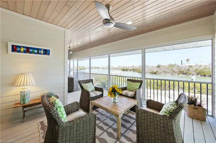 Sunroom / solarium featuring a water view, ceiling fan, and wooden ceiling