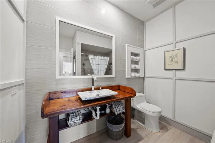Bathroom with sink, tile walls, curtained shower, and toilet