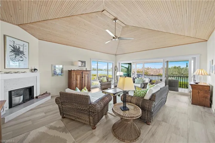 Living room with a wealth of natural light, light hardwood / wood-style floors, high vaulted ceiling, and wooden ceiling