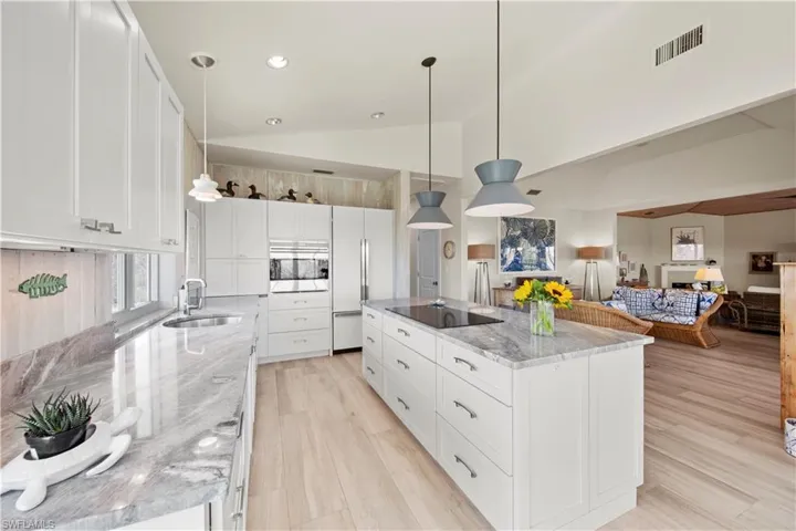 Kitchen with sink, a center island, black electric cooktop, pendant lighting, and white cabinets