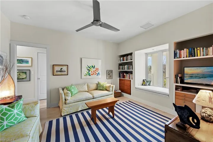 Living room with built in shelves, ceiling fan, and light hardwood / wood-style floors