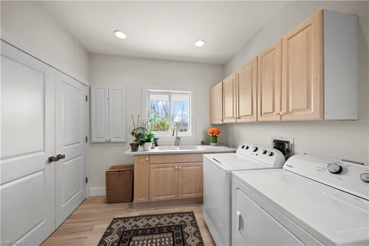 Laundry room featuring cabinets, light hardwood / wood-style floors, sink, and washing machine and dryer