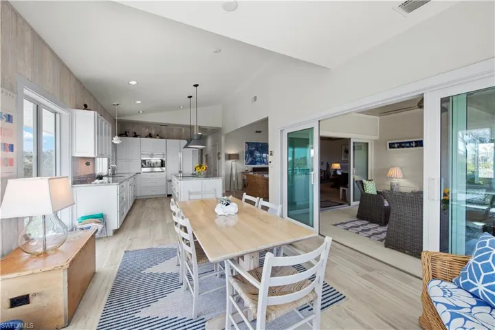 Dining room with sink, light hardwood / wood-style floors, and high vaulted ceiling