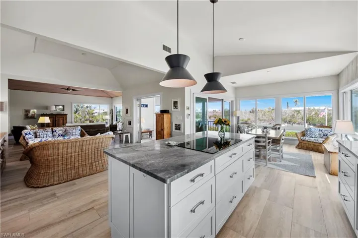 Kitchen with a kitchen island, decorative light fixtures, white cabinets, light hardwood / wood-style floors, and black electric cooktop