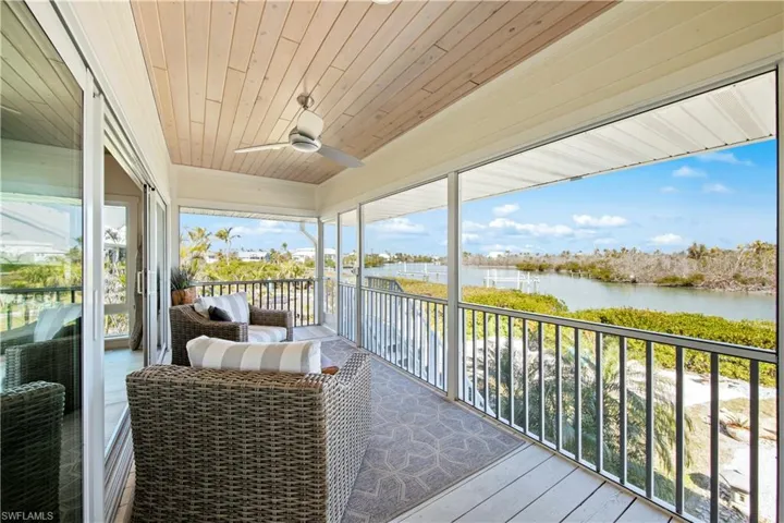 Sunroom featuring wood ceiling, ceiling fan, and a water view