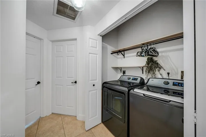 Clothes washing area featuring washing machine and clothes dryer, electric dryer hookup, and light tile floors