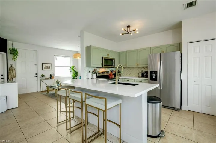 Kitchen featuring stainless steel appliances, tasteful backsplash, light tile flooring, and kitchen peninsula