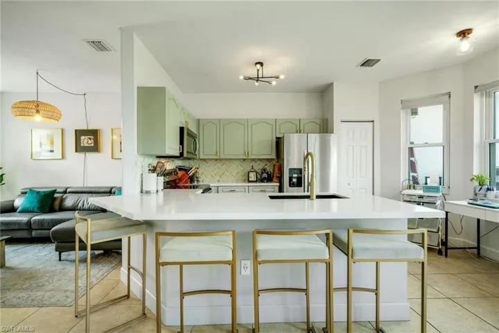 Kitchen with stainless steel appliances, kitchen peninsula, sink, tasteful backsplash, and light tile floors
