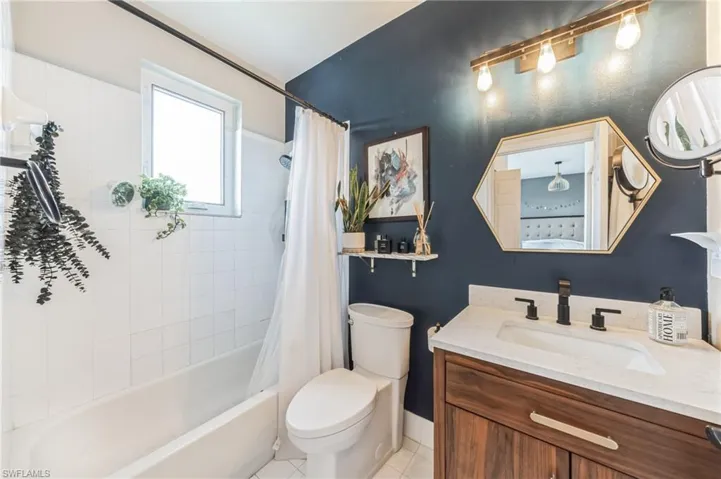 Full bathroom featuring tile floors, shower / bath combination with curtain, toilet, and vanity