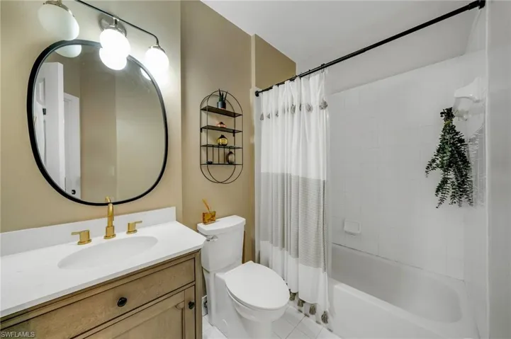 Full bathroom featuring tile floors, shower / tub combo, toilet, and vanity with extensive cabinet space
